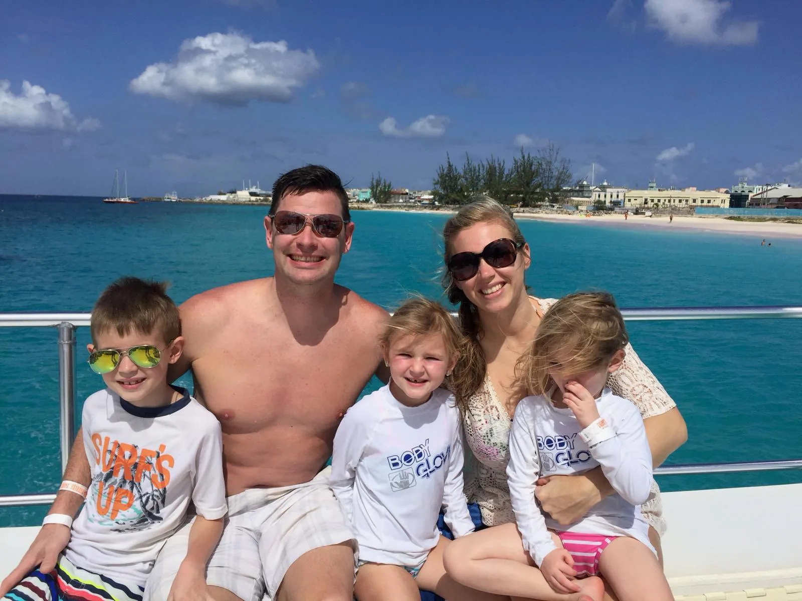 A family on the boat's rail with the Bridgetown waterfront behind them