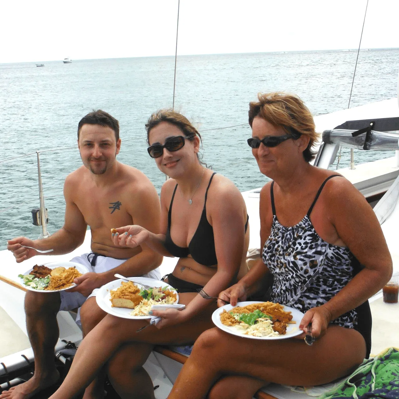 Guests eating the hot buffet lunch on deck while the catamaran lies at anchor