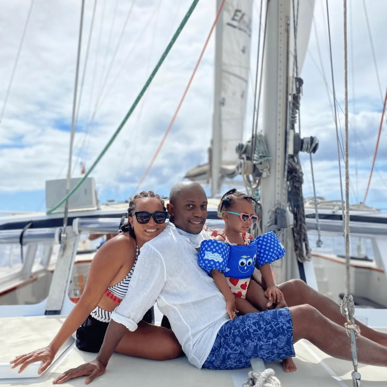 A family sitting on the catamaran's foredeck beneath the rigging, the youngest in armbands